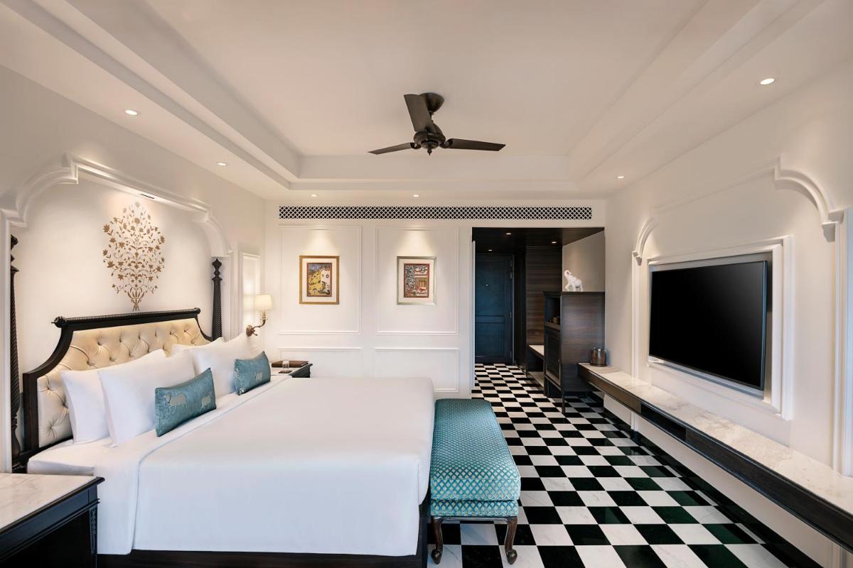 a bedroom with a white bed and a flat screen tv at Aurika, Udaipur - Luxury by Lemon Tree Hotels in Udaipur