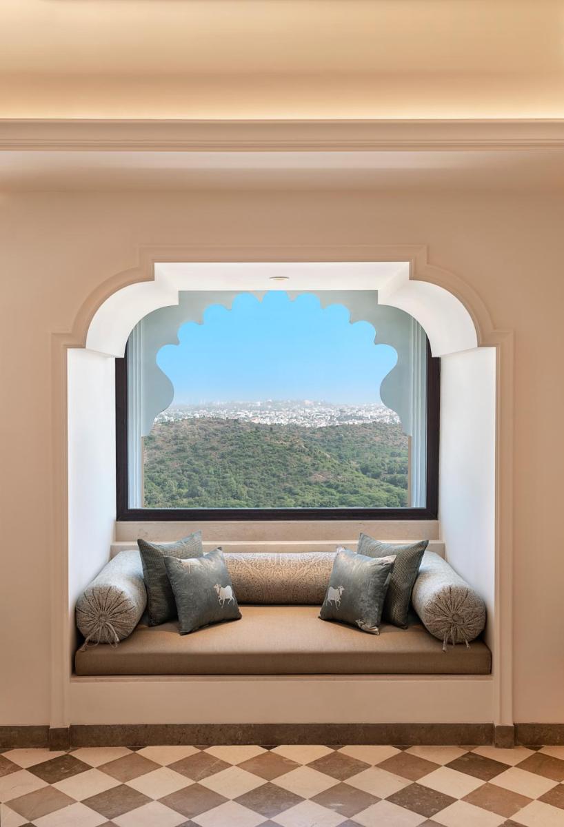 a window seat with pillows sitting in front of a window at Aurika, Udaipur - Luxury by Lemon Tree Hotels in Udaipur