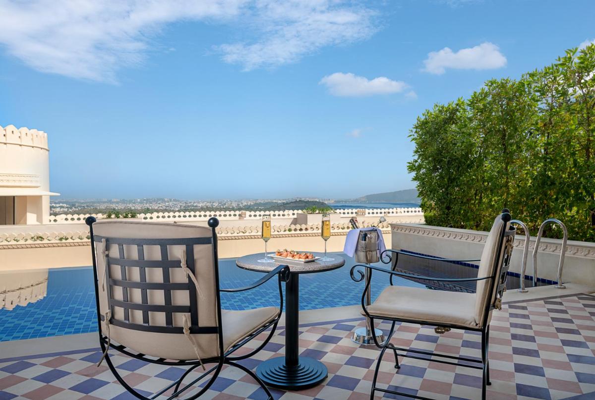 a patio with two chairs and a table and a view of the water at Aurika, Udaipur - Luxury by Lemon Tree Hotels in Udaipur