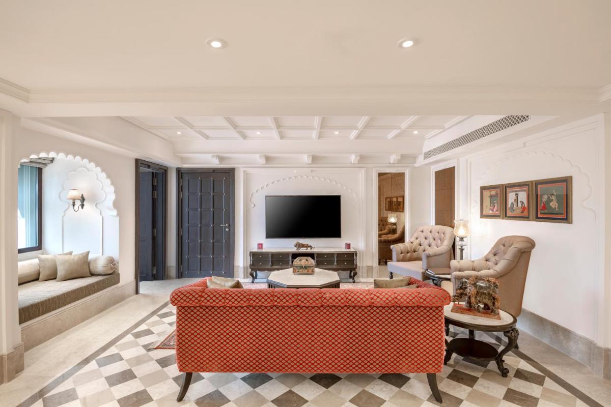 a living room with a red couch and a tv at Aurika, Udaipur - Luxury by Lemon Tree Hotels in Udaipur