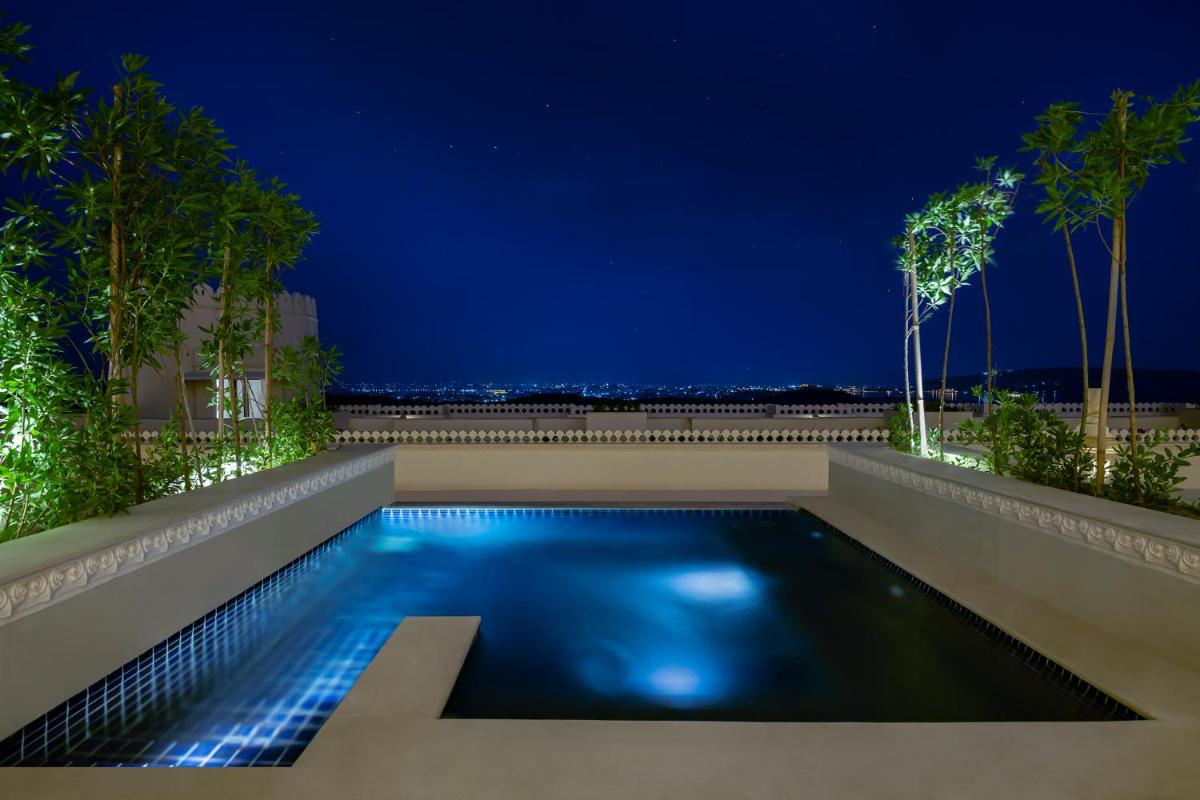 a swimming pool in the backyard of a house at night at Aurika, Udaipur - Luxury by Lemon Tree Hotels in Udaipur