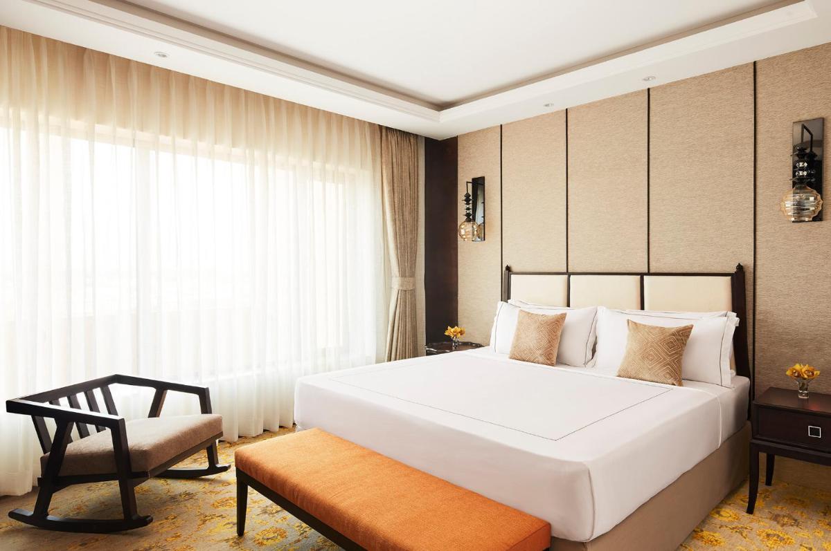 a bedroom with a large white bed and a chair at Taj Tirupati in Tirupati