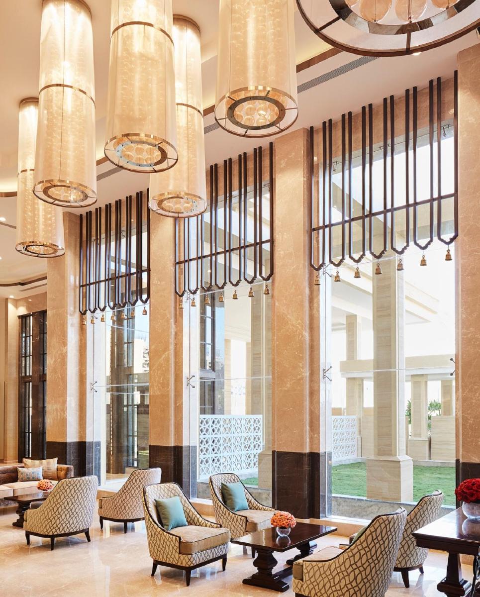 a lobby with chairs and tables and chandeliers at Taj Tirupati in Tirupati