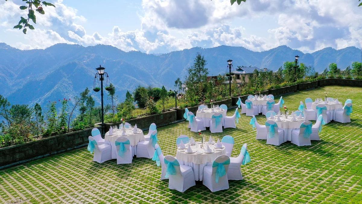 a group of tables and chairs on a patio with mountains at Welcomhotel by ITC Hotels, Shimla in Shimla