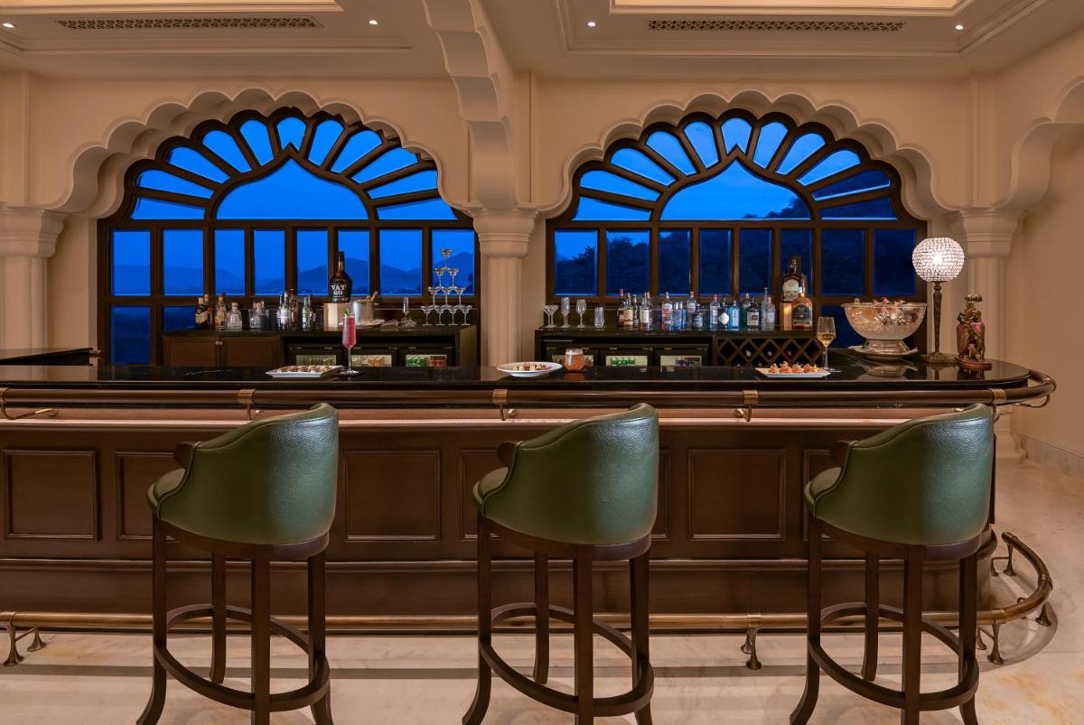 a bar with green chairs in front of two windows at Aurika, Udaipur - Luxury by Lemon Tree Hotels in Udaipur
