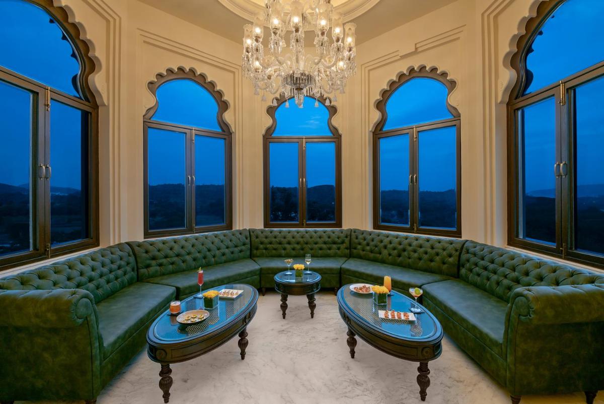 a living room with green furniture and large windows at Aurika, Udaipur - Luxury by Lemon Tree Hotels in Udaipur