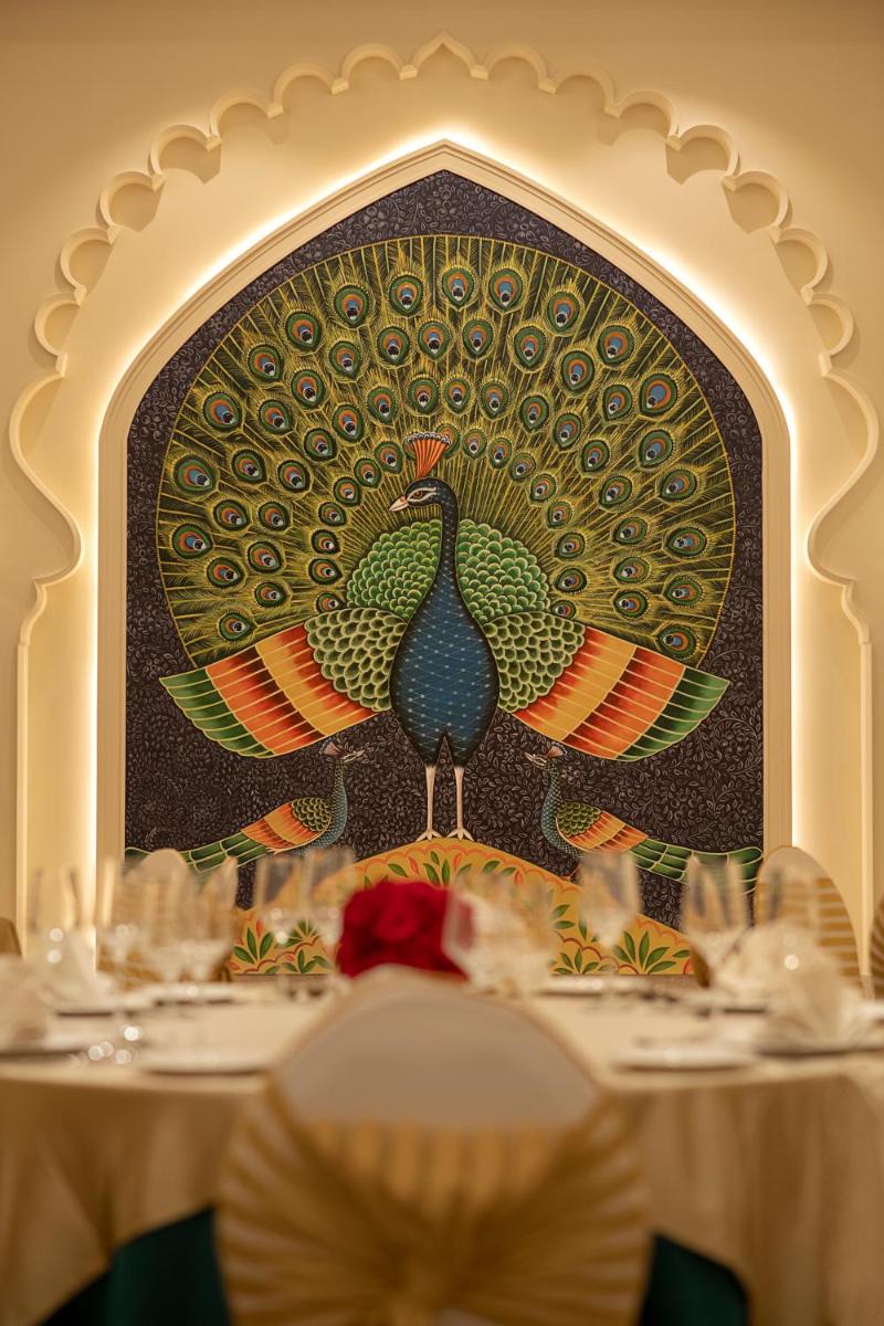 a painting of two peacocks on a wall in a restaurant at Aurika, Udaipur - Luxury by Lemon Tree Hotels in Udaipur
