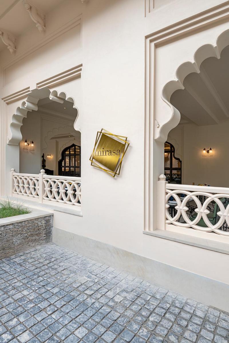 a white house with a window and a brick sidewalk at Aurika, Udaipur - Luxury by Lemon Tree Hotels in Udaipur