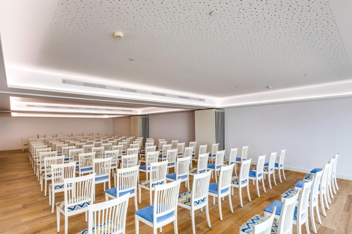 una habitación vacía con hileras de sillas y mesas blancas en Hotel Coronado Thalasso & Spa, en Paguera