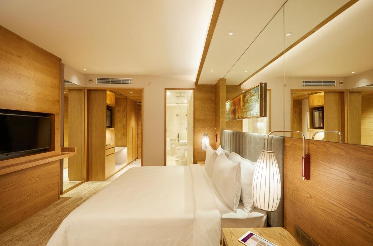 a bedroom with a large white bed and a television at The Residency Towers in Chennai