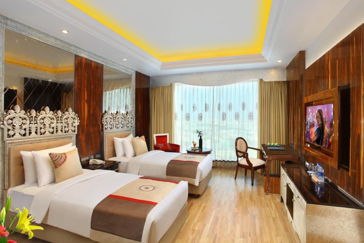 a hotel room with two beds and a desk at Seven Seas Hotel in New Delhi