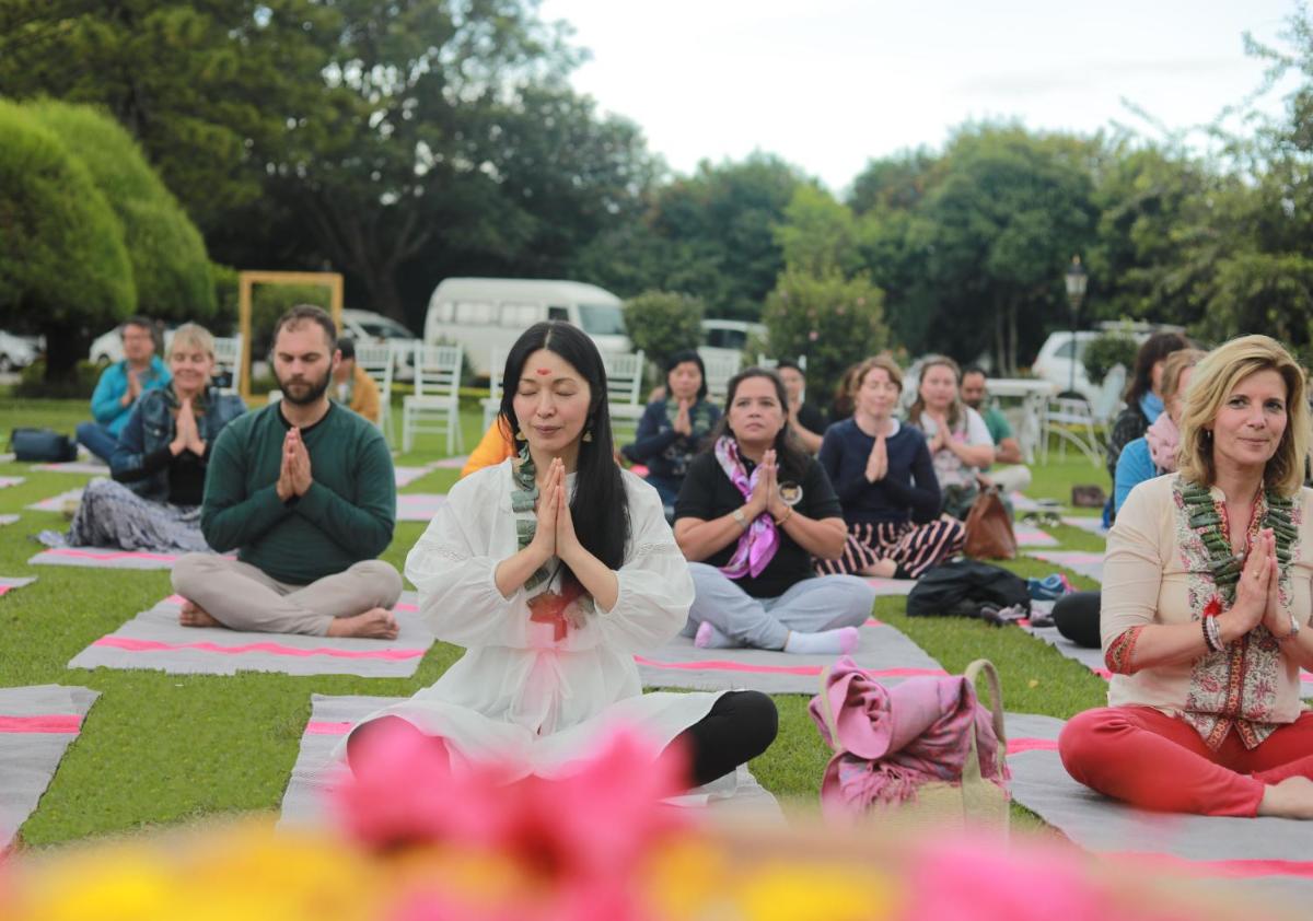 a group of people sitting on the grass doing yoga at Savoy - IHCL SeleQtions in Ooty