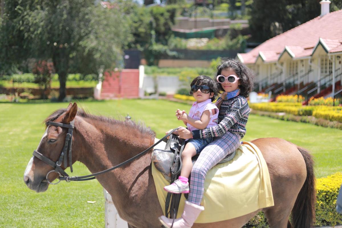 a woman and a child riding a horse at Savoy - IHCL SeleQtions in Ooty