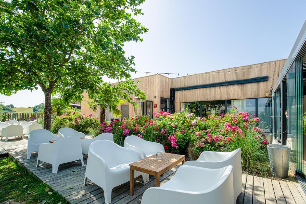 d'un patio avec des chaises blanches, des tables et des fleurs. dans l'établissement Le Domaine de Baulieu, Singuliers Hotels, à Auch 31 autres photos