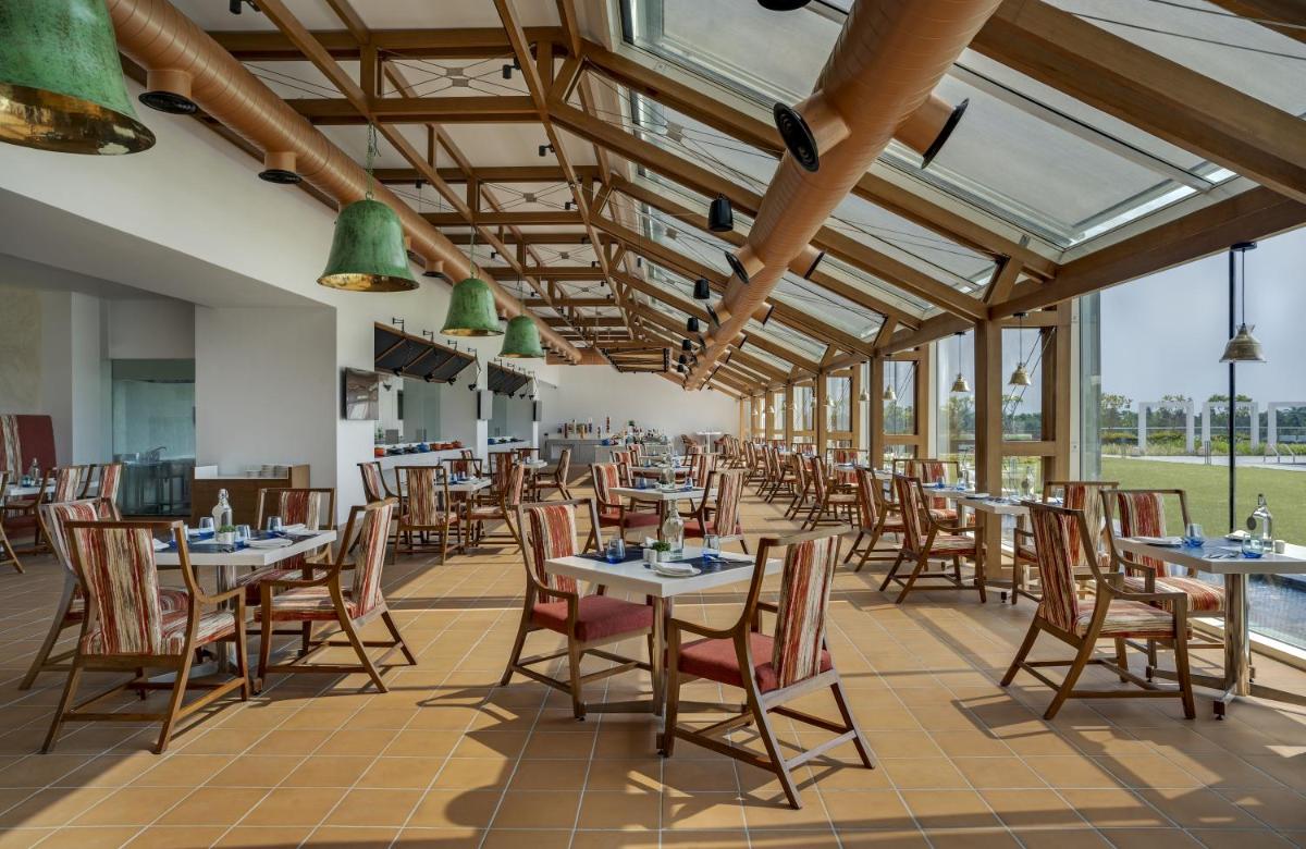 a dining room with tables and chairs and windows at O by Tamara, Trivandrum in Trivandrum