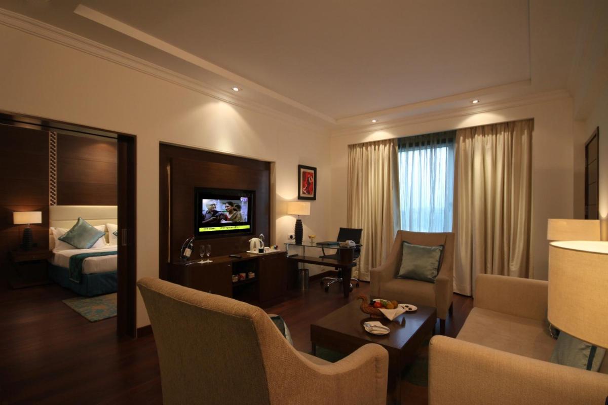 a hotel room with a bedroom and a living room at Radisson Jaipur City Center in Jaipur