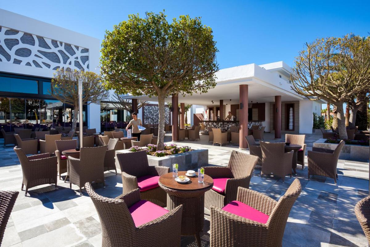 un patio en un restaurante con mesas y sillas en Hotel Riu Chiclana - All Inclusive, en Chiclana de la Frontera
