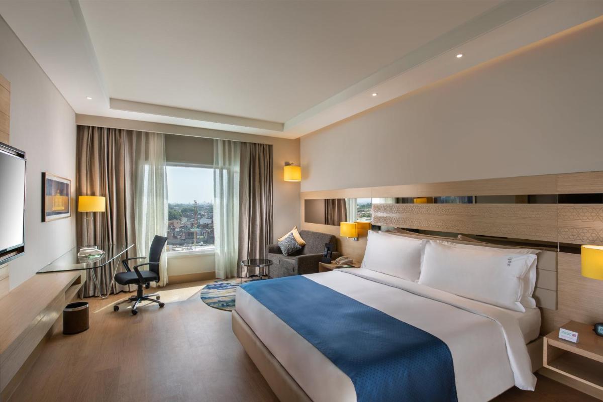 a hotel room with a large bed and a desk at Holiday Inn Agra MG Road an IHG Hotel in Agra