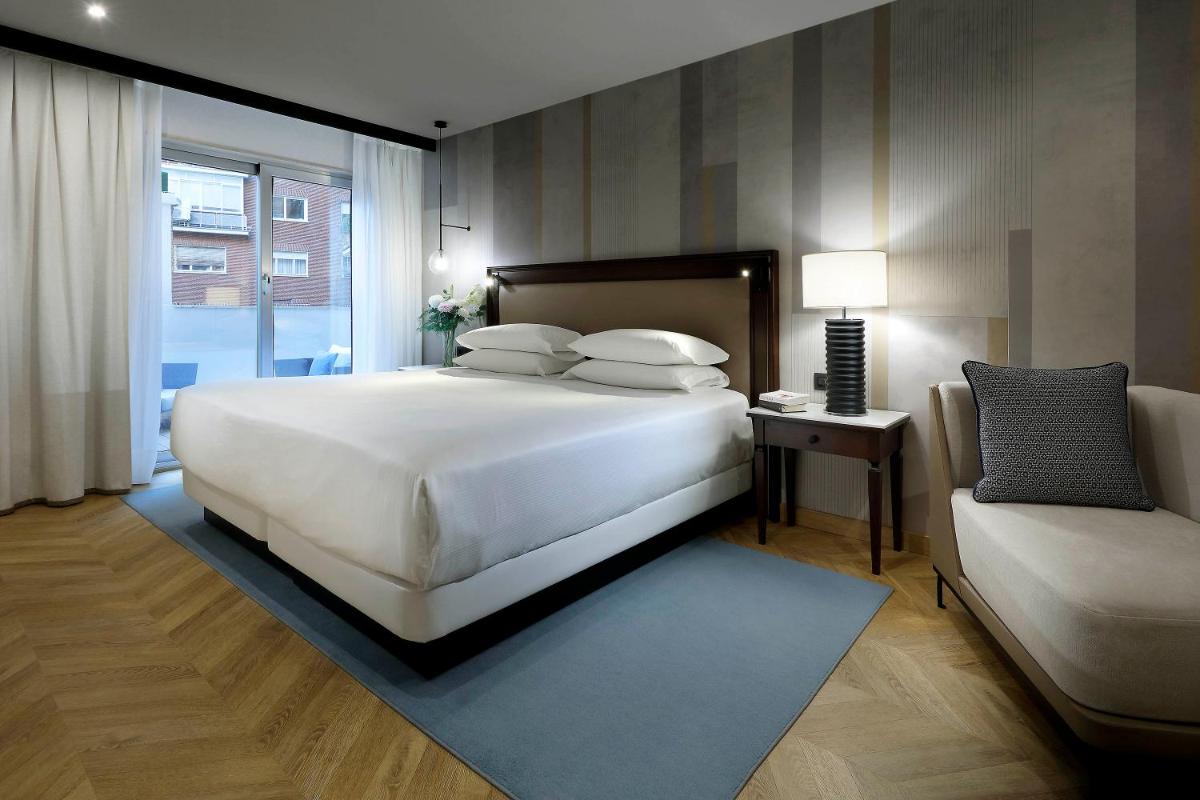 Un dormitorio con una gran cama blanca y un sofá. en Hyatt Regency Hesperia Madrid, en Madrid