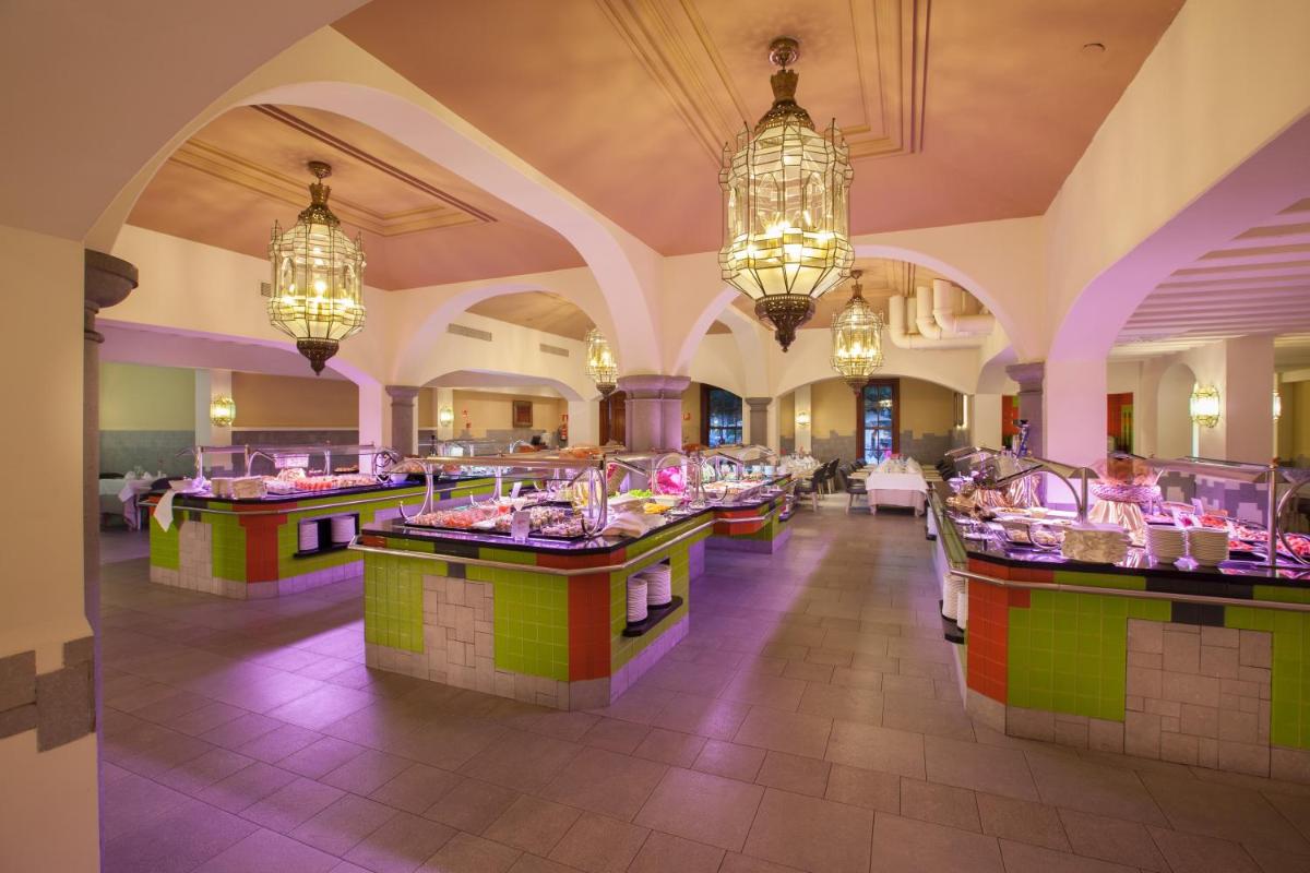 un restaurante con contadores coloridos y lámparas de araña en Lopesan Villa del Conde Resort & Thalasso, en Meloneras