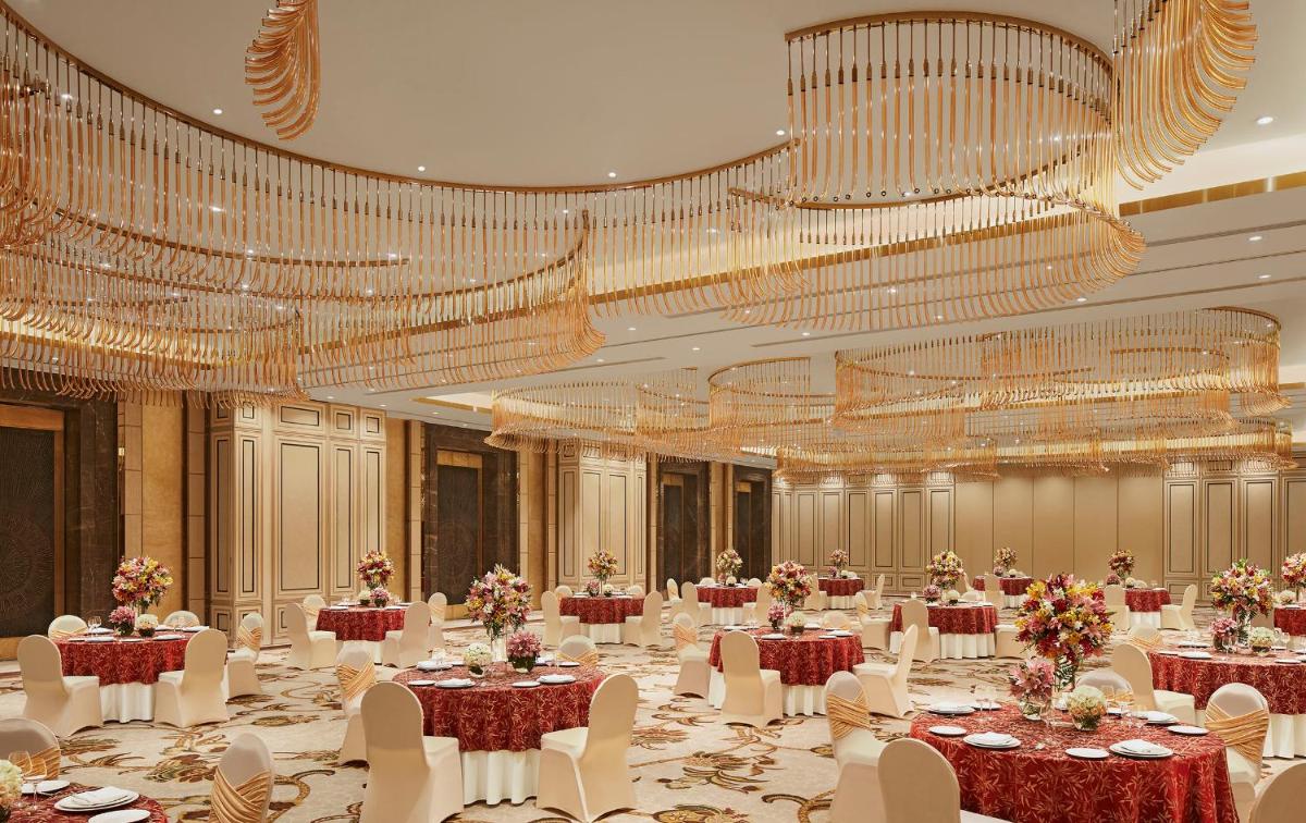 a banquet hall with tables and chairs and chandeliers at Taj Tirupati in Tirupati