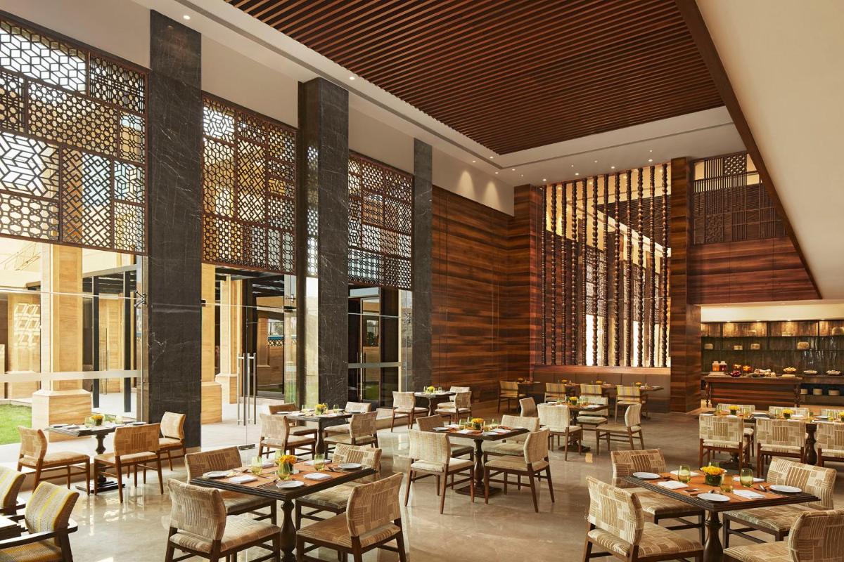 a dining room with tables and chairs and windows at Taj Tirupati in Tirupati