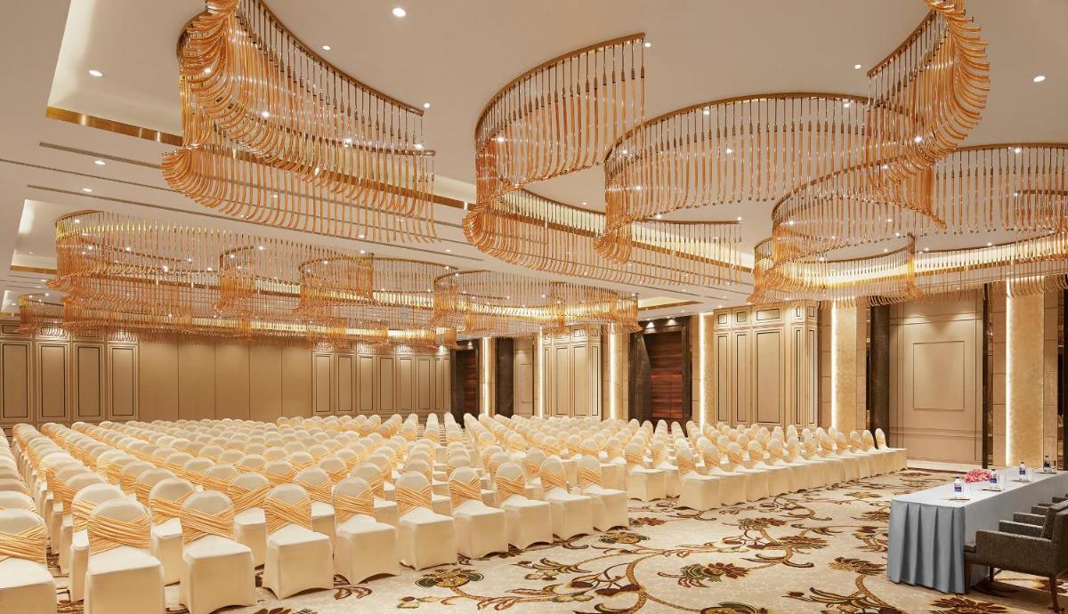 a large banquet hall with white chairs and chandeliers at Taj Tirupati in Tirupati
