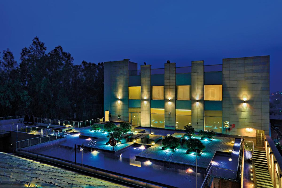 a building with a pool in front of it at night at Radisson Blu Hotel, Greater Noida in Greater Noida