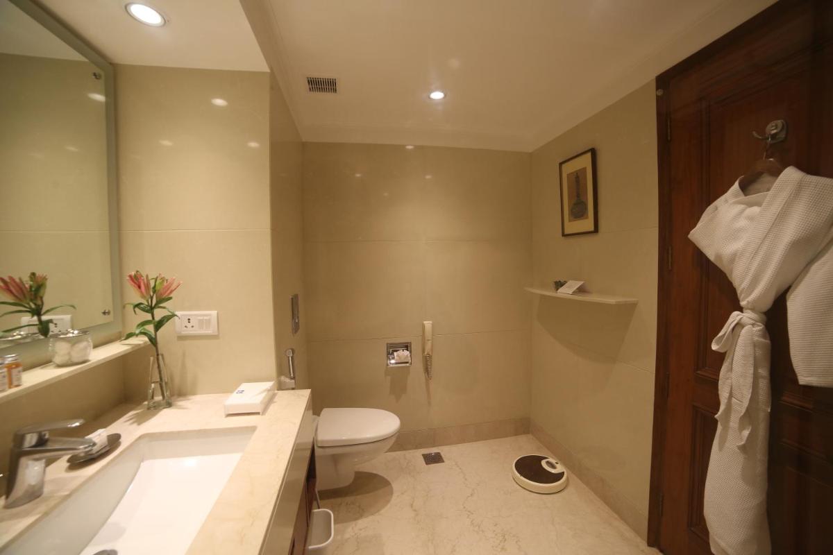 a bathroom with a toilet and a sink and a tub at Jaypee Palace Hotel in Agra