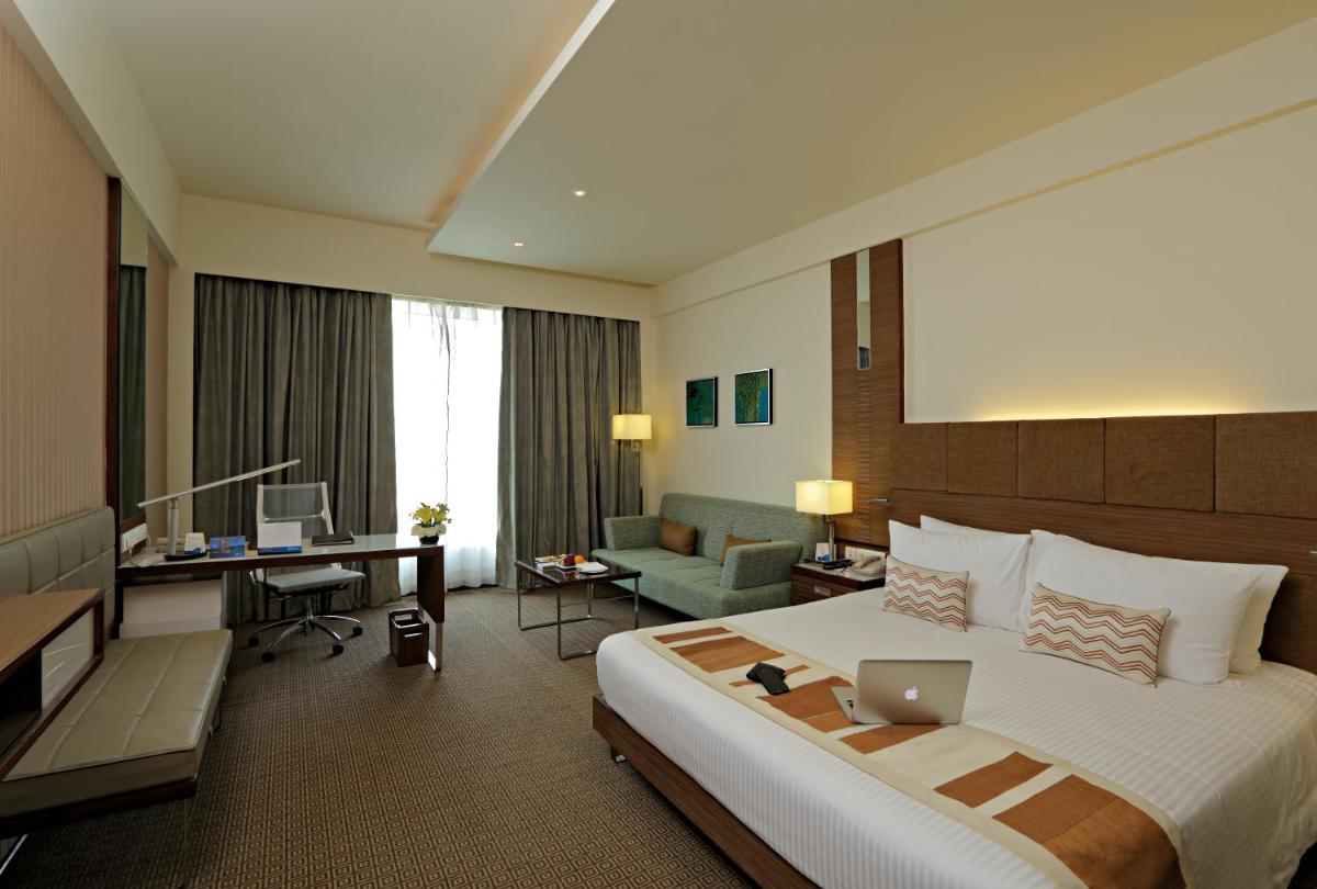 a hotel room with a large bed and a desk at Radisson Blu Hotel, Greater Noida in Greater Noida