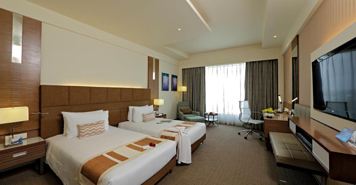 a hotel room with two beds and a television at Radisson Blu Hotel, Greater Noida in Greater Noida