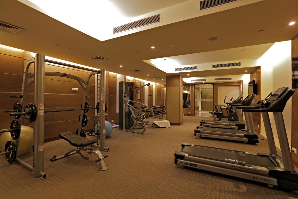 a gym with a row of treadms and cardio machines at Radisson Blu Hotel, Greater Noida in Greater Noida