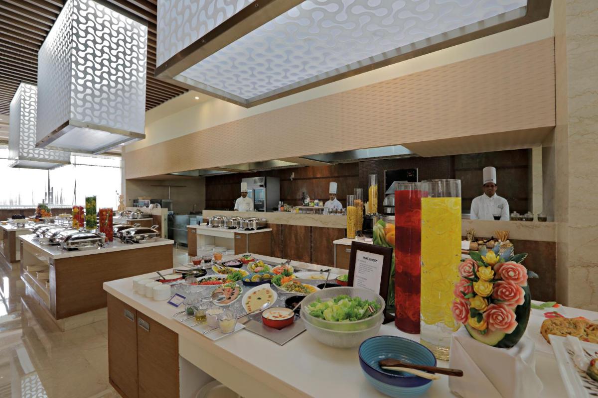 a large kitchen with many plates of food on a counter at Radisson Blu Hotel, Greater Noida in Greater Noida