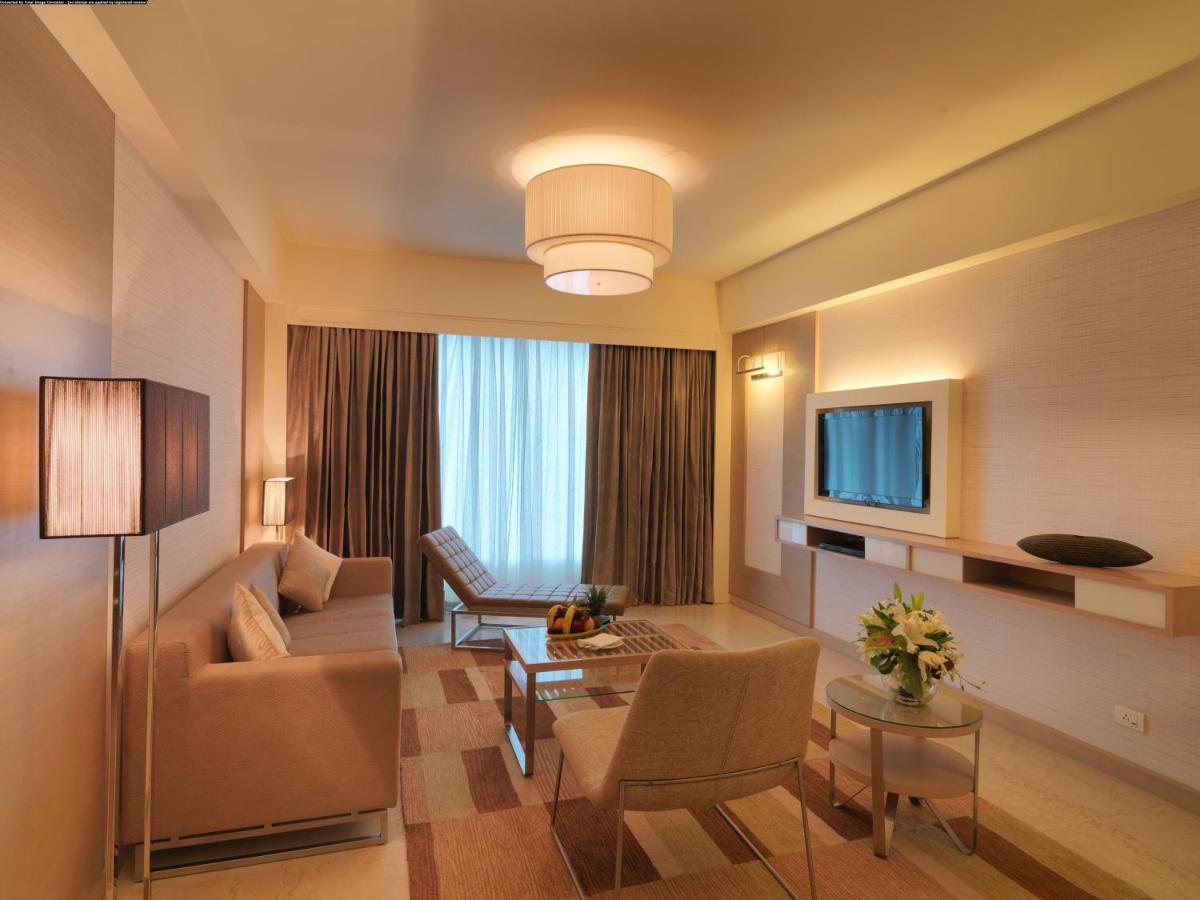 a living room with a couch and a tv at Radisson Blu Hotel, Greater Noida in Greater Noida