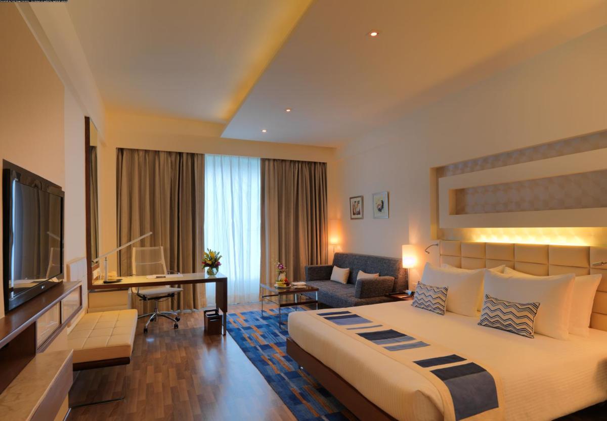 a hotel room with a large bed and a television at Radisson Blu Hotel, Greater Noida in Greater Noida