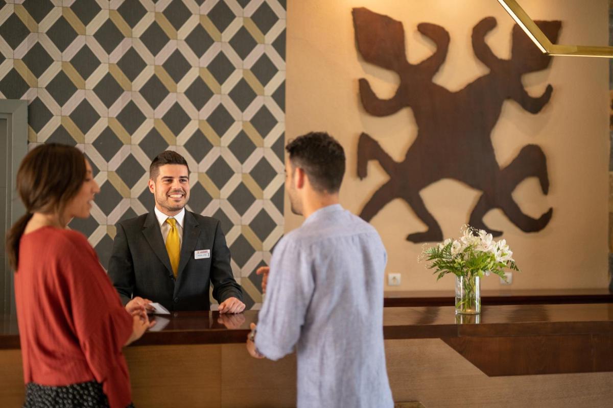 Un hombre con traje y una mujer de pie en un mostrador. en Hotel Valle del Este, en Vera 91 fotos más