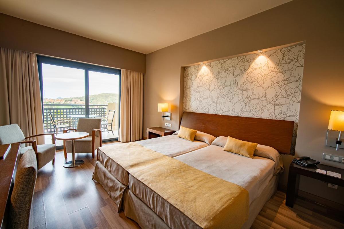 Una habitación de hotel con una cama grande y una ventana grande. en Hotel Valle del Este, en Vera