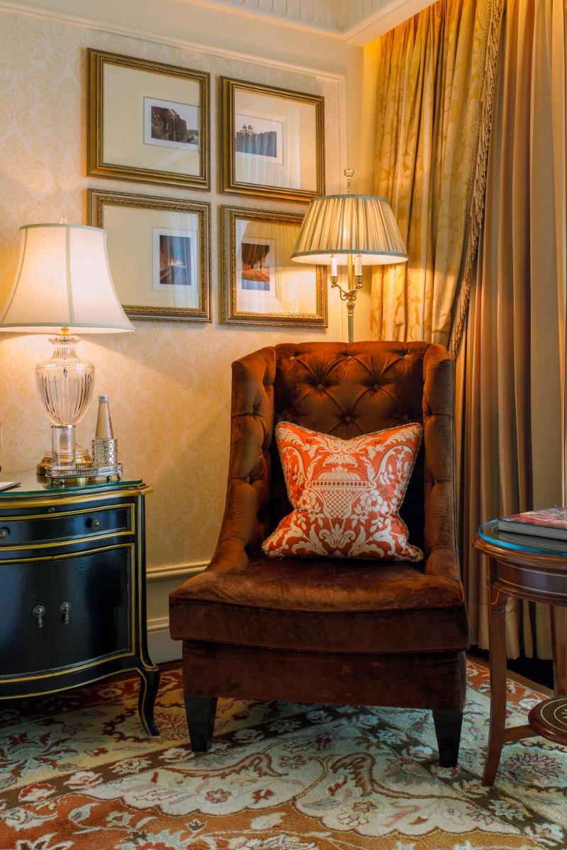 a chair with a pillow on it in a room at The Leela Palace New Delhi in New Delhi a chair with a pillow on it in a room at The Leela Palace New Delhi in New Delhi