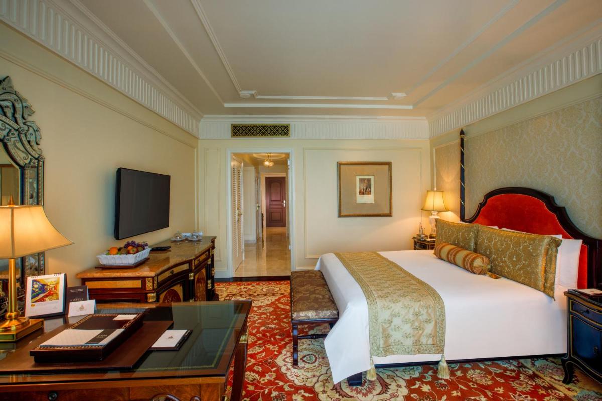 a bedroom with a bed and a desk and a television at The Leela Palace New Delhi in New Delhi a bedroom with a bed and a desk and a television at The Leela Palace New Delhi in New Delhi