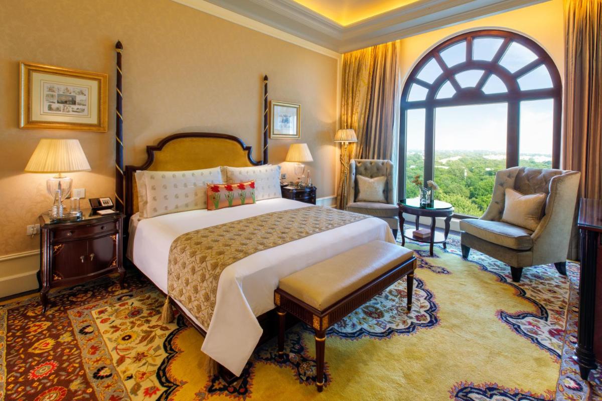 a bedroom with a large bed and a large window at The Leela Palace New Delhi in New Delhi a bedroom with a large bed and a large window at The Leela Palace New Delhi in New Delhi
