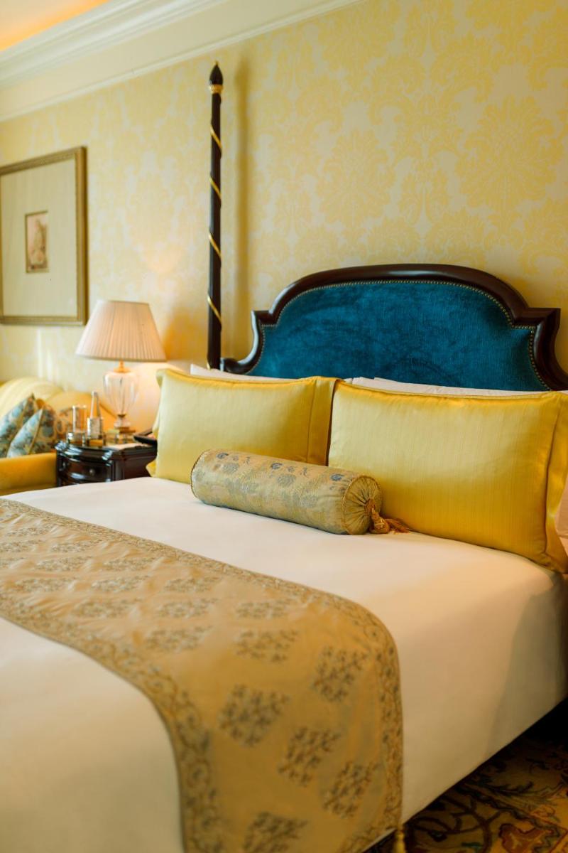 a bedroom with a large bed with a blue headboard at The Leela Palace New Delhi in New Delhi a bedroom with a large bed with a blue headboard at The Leela Palace New Delhi in New Delhi