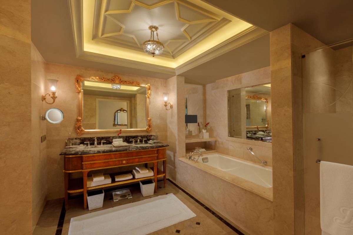 a bathroom with a sink and a tub and a mirror at The Leela Palace New Delhi in New Delhi a bathroom with a sink and a tub and a mirror at The Leela Palace New Delhi in New Delhi