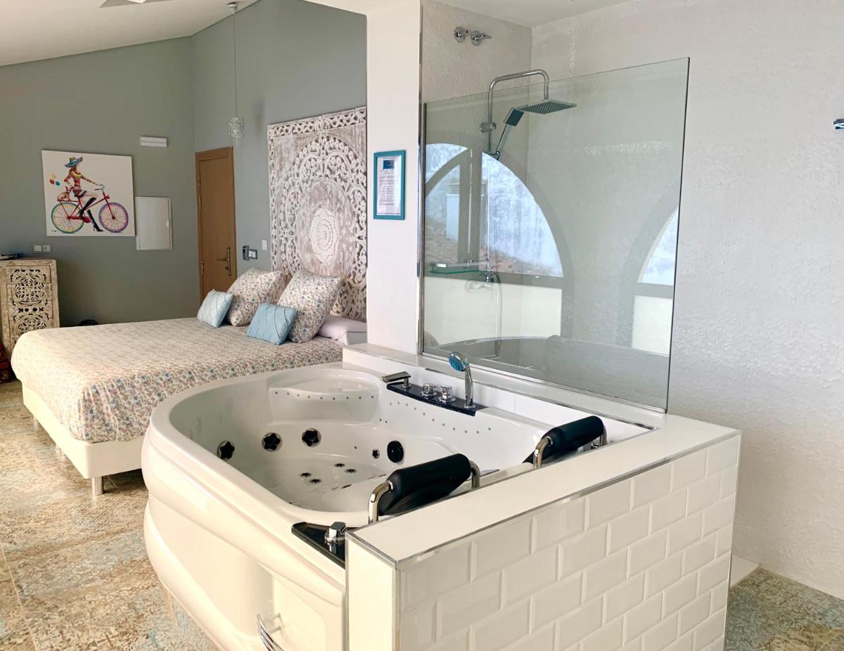 bañera grande en un dormitorio con cama en Akla Hotel Mérida, en Mérida