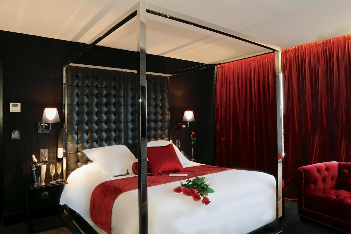 - une chambre avec un lit à baldaquin et un rideau rouge dans l'établissement Oz'Inn Hôtel & Spa, au Cap d'Agde