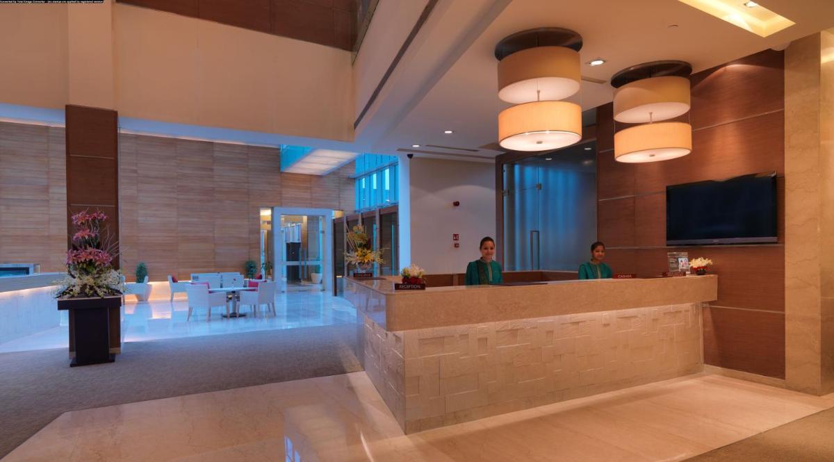 a lobby of a hotel with people sitting at a counter at Radisson Blu Hotel, Greater Noida in Greater Noida