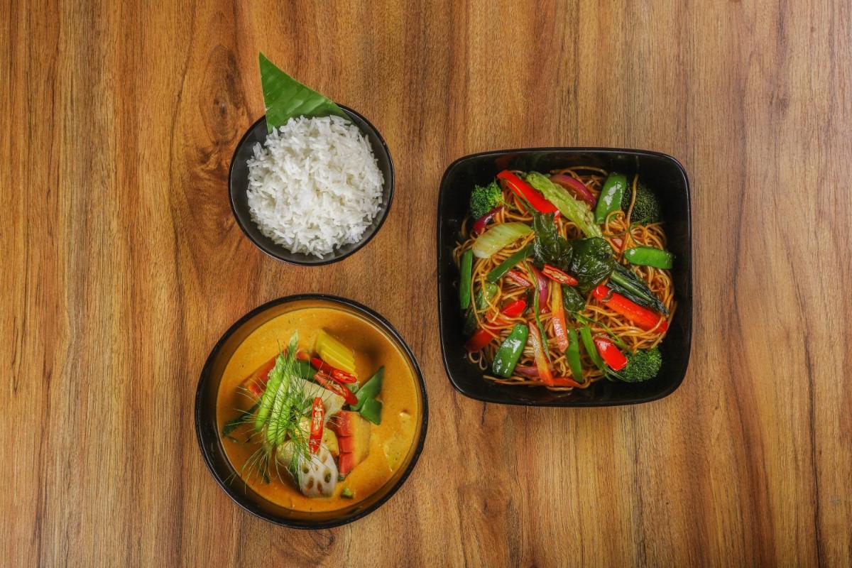 three bowls of food and rice on a wooden table at Lemon Tree Premier, Delhi Airport in New Delhi three bowls of food and rice on a wooden table at Lemon Tree Premier, Delhi Airport in New Delhi