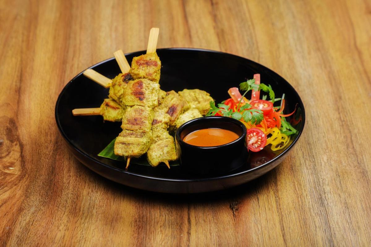 a black plate of food with meat skewers and salad at Lemon Tree Premier, Delhi Airport in New Delhi a black plate of food with meat skewers and salad at Lemon Tree Premier, Delhi Airport in New Delhi