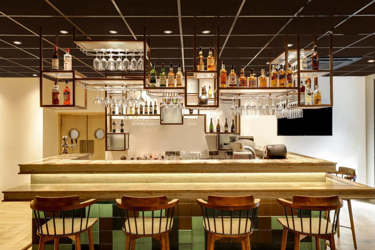 a bar with chairs and a counter with drinks at Lemon Tree Premier, Delhi Airport in New Delhi a bar with chairs and a counter with drinks at Lemon Tree Premier, Delhi Airport in New Delhi