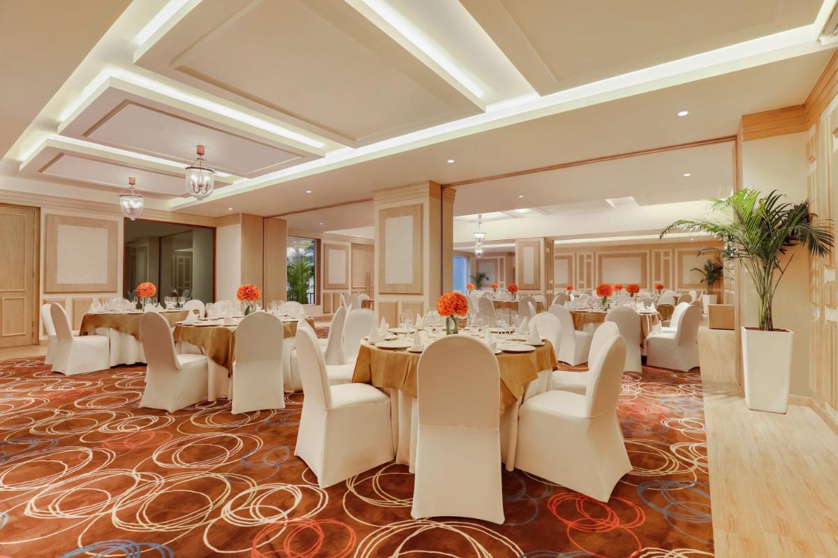 a banquet hall with tables and white chairs at Lemon Tree Premier, Delhi Airport in New Delhi a banquet hall with tables and white chairs at Lemon Tree Premier, Delhi Airport in New Delhi