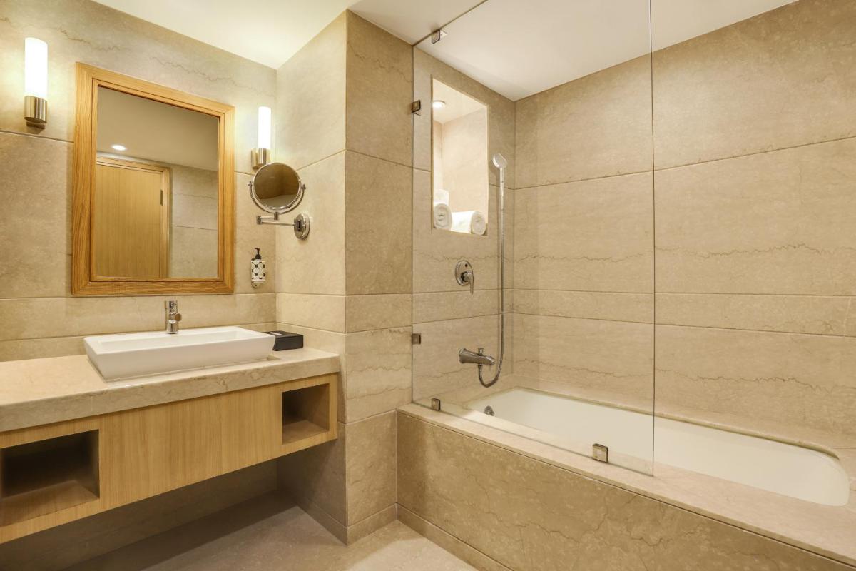 a bathroom with a sink and a bath tub at Lemon Tree Premier, Delhi Airport in New Delhi a bathroom with a sink and a bath tub at Lemon Tree Premier, Delhi Airport in New Delhi
